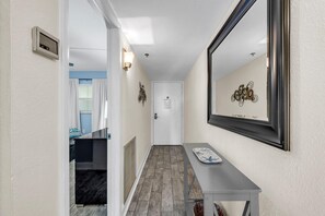 A hallway with a door, a bench, and a wall-mounted mirror. - Holiday Villas III #709 (Indian Shores)