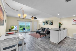 A modern living space with a dining area, a kitchen, and a balcony with a view. - Holiday Villas III #709 (Indian Shores)