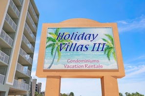 A sign for Holiday Villas III, indicating it offers condominiums and vacation rentals. - Holiday Villas III #709 (Indian Shores)