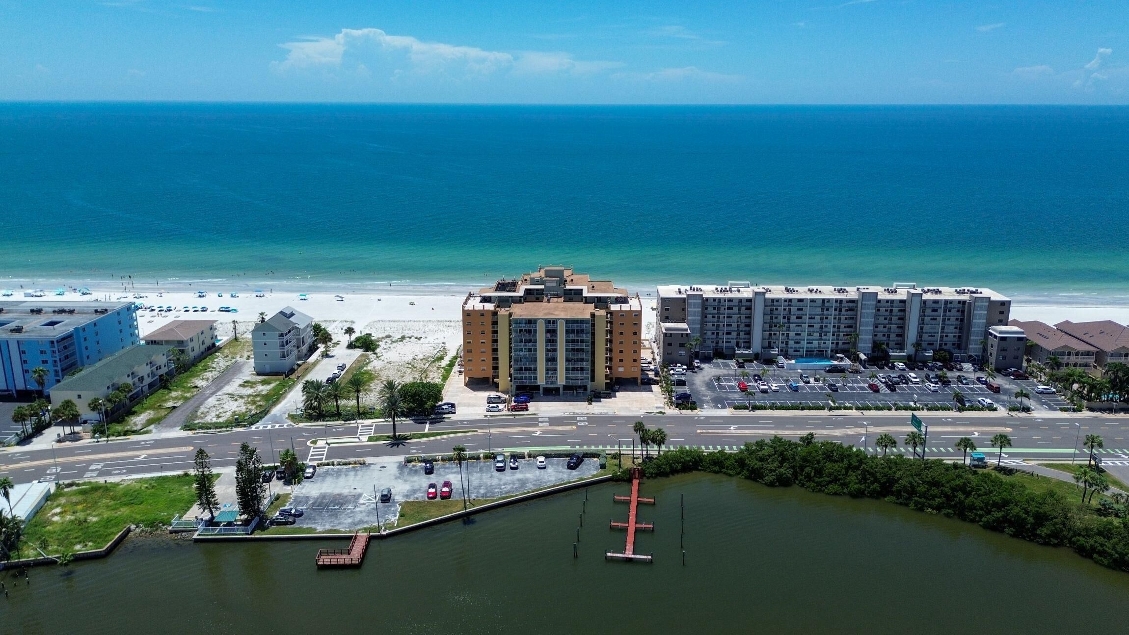 A coastal hotel with multiple buildings, a parking lot, and a view of the ocean.