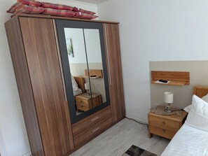 Ein Schlafzimmer mit Holzschrank, Nachttisch, Lampe und einem Bett.