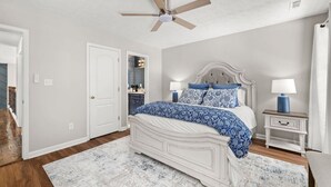A bedroom with a bed, bedside tables, a ceiling fan, and a door. - Wake. Lakeview. Repeat. Luxury-5-bedroom/4 bath (Fayetteville)
