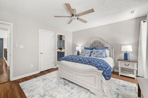 A bedroom with a bed, bedside tables, a ceiling fan, and a door. - Wake. Lakeview. Repeat. Luxury-5-bedroom/4 bath (Fayetteville)