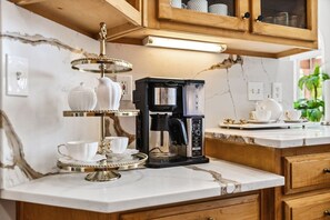 A kitchen with a coffee maker, a tea set, and a marble countertop. - Wake. Lakeview. Repeat. Luxury-5-bedroom/4 bath (Fayetteville)