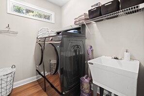 A laundry area with a washing machine, a drying rack, a sink, and a window. - Wake. Lakeview. Repeat. Luxury Holiday Getaway (Fayetteville)