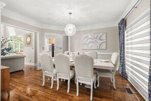 A dining room with a round table, six chairs, a chandelier, and a view of the outdoors. - Wake. Lakeview. Repeat. Luxury-5-bedroom/4 bath (Fayetteville)