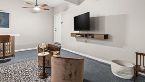 A modern living room with a flat-screen TV mounted on the wall, a ceiling fan, and a patterned rug. - Wake. Lakeview. Repeat. Luxury-5-bedroom/4 bath (Fayetteville)