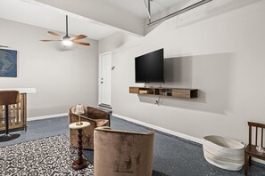 A modern living room with a flat-screen TV mounted on the wall, a ceiling fan, and a patterned rug. - Wake. Lakeview. Repeat. Luxury-5-bedroom/4 bath (Fayetteville)