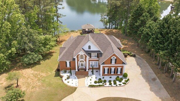 A large, two-story house with a symmetrical facade, a central entrance, and a driveway leading to a gated driveway. - Wake. Lakeview. Repeat. Luxury-5-bedroom/4 bath (Fayetteville)