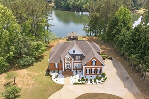 A large, two-story house with a symmetrical facade, a central entrance, and a driveway leading to a gated driveway. - Wake. Lakeview. Repeat. Luxury Holiday Getaway (Fayetteville)