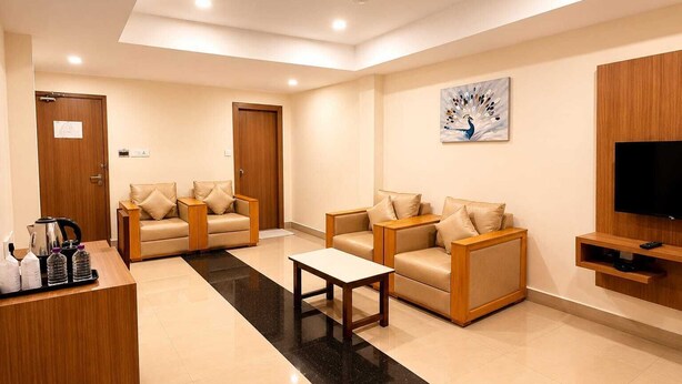 Un hall de hotel con mostrador de recepción, dos sofás, una mesa de centro, un cuadro y un televisor montado en la pared.