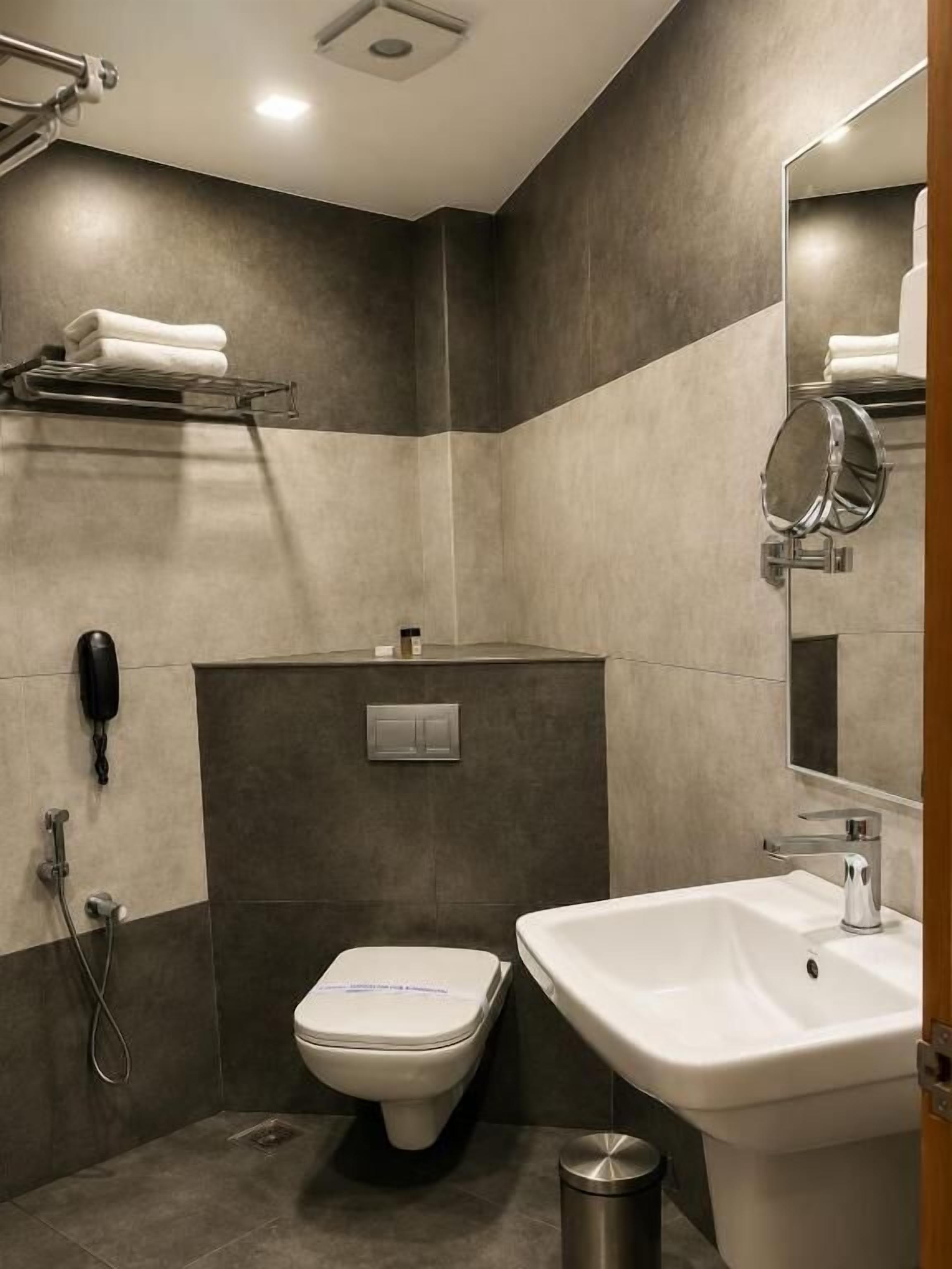 A modern bathroom with a toilet, sink, and mirror.