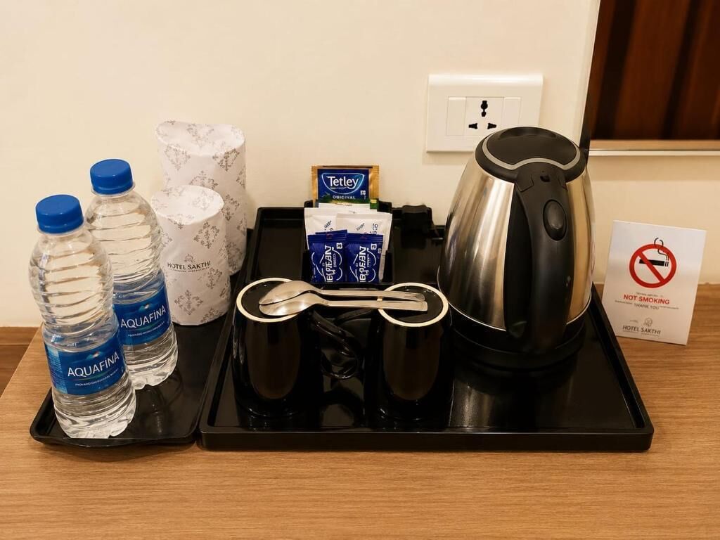 Bandeja de desayuno en una habitación de hotel con botellas de agua, cafetera, sobres de té y un cartel de 'No Fumar'.