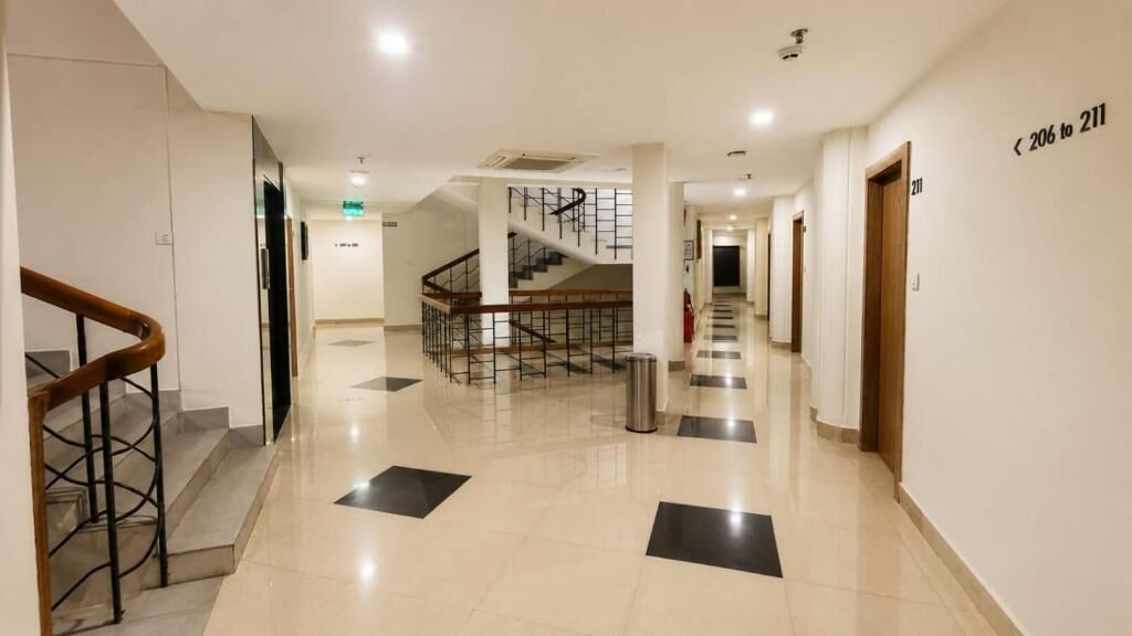 A hotel corridor with a staircase, a fire extinguisher, and a sign indicating room numbers 206 to 211.