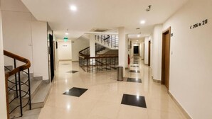 Pasillo de hotel con una escalera, un extintor y un letrero que indica los números de habitaciones del 206 al 211.