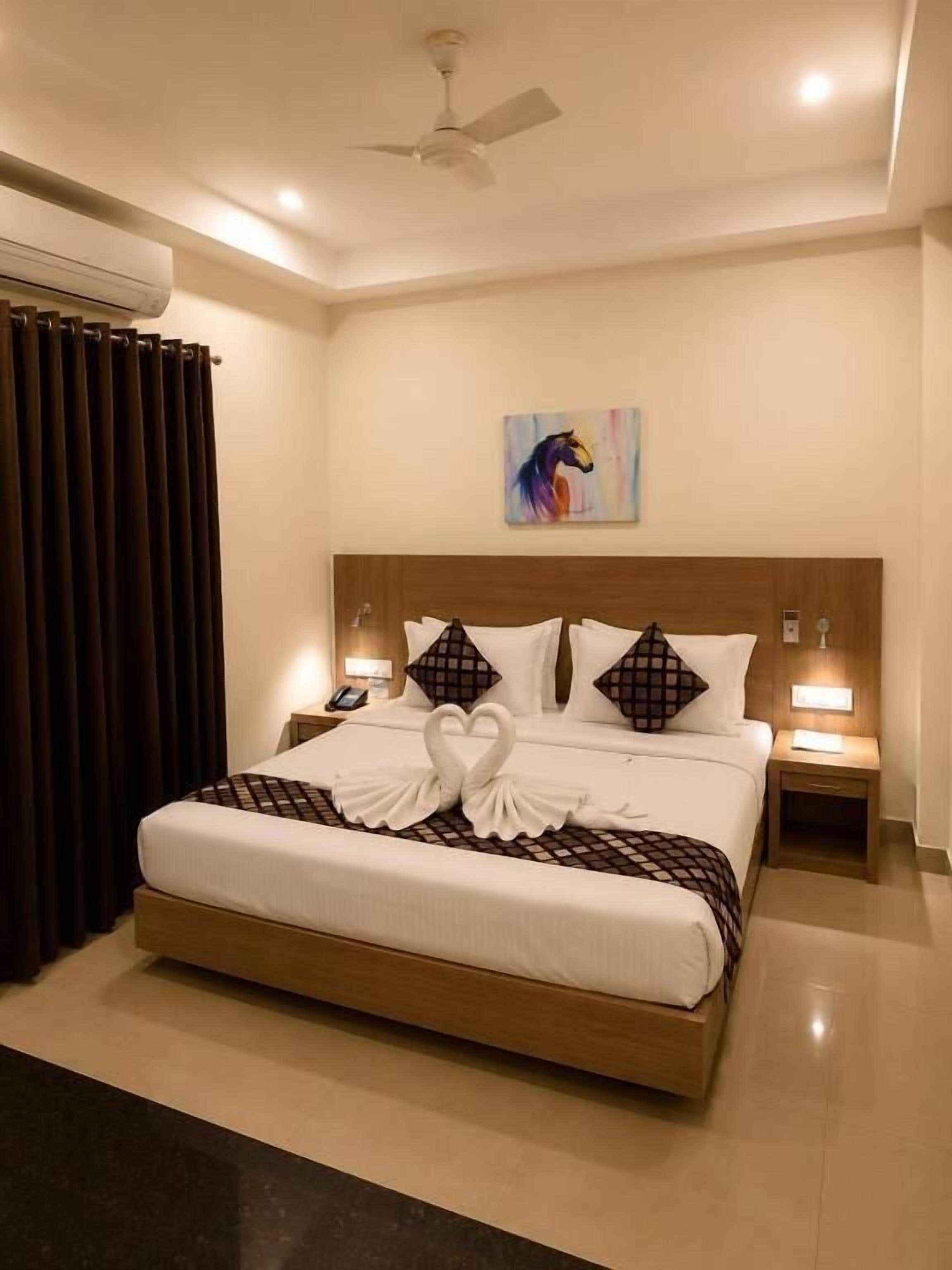 Habitación de hotel con una cama grande, dos mesitas de noche, un ventilador de techo y un cuadro en la pared.