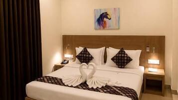 Habitación de hotel con una cama grande, dos mesitas de noche, un ventilador de techo y un cuadro en la pared.