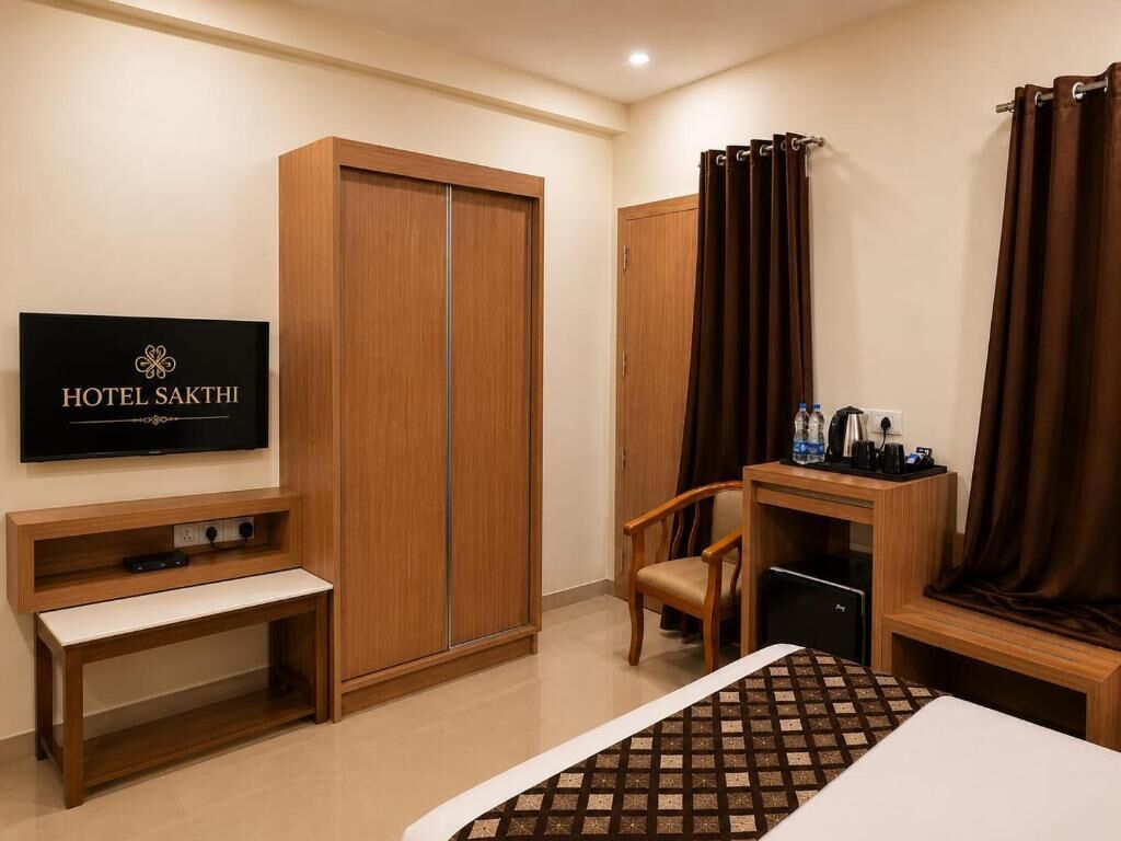 Habitación de hotel con cama, televisor, escritorio y silla, armario y cortinas.