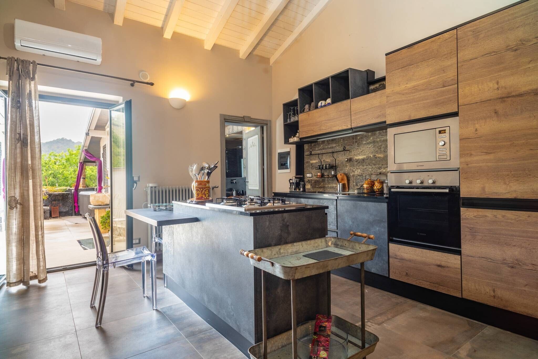 Een moderne keuken met een centraal kookeiland, inbouwapparatuur en uitzicht op de omgeving.