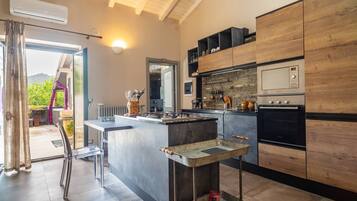 Een moderne keuken met een centraal kookeiland, inbouwapparatuur en uitzicht op de omgeving.