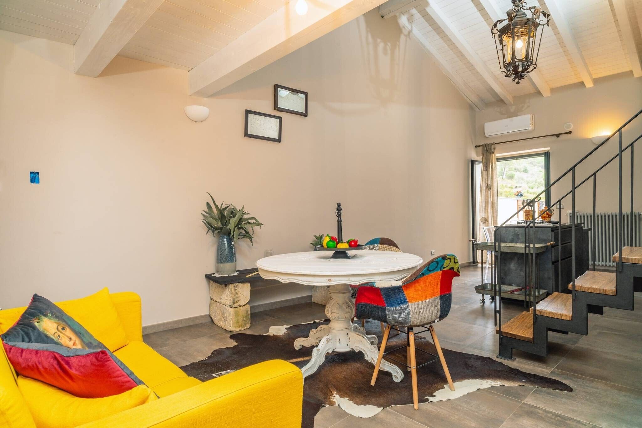 Een modern interieur met een ronde eettafel, een gele bank en een trap.
