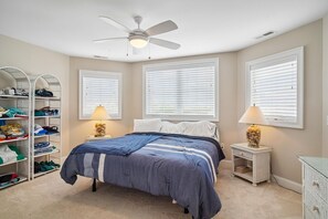 Ein Schlafzimmer mit einem Bett, einem Deckenventilator, einem Kleiderschrank und zwei Nachttischlampen.