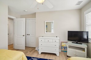 Ein Schlafzimmer mit Bett, Kommode, Fernseher und Deckenventilator.