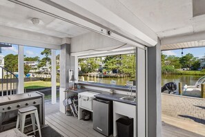 An outdoor kitchen area with a grill, sink, and a view of a lake. - Welcome to your Canal Front Oasis in South Bethany! (South Bethany)
