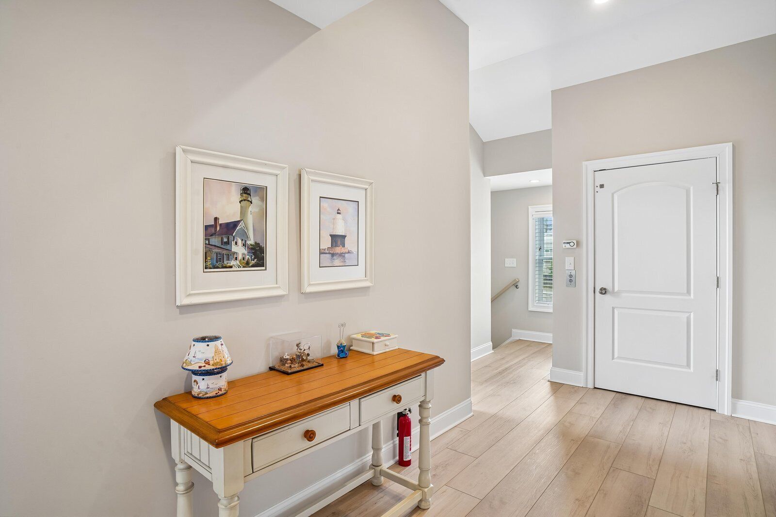 A hallway with a wooden console table, framed artwork, and a white door.