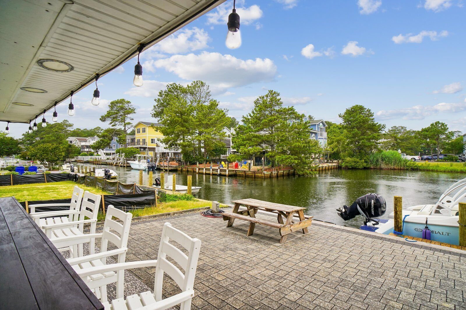 A waterfront patio with outdoor seating, a dock, and boats.