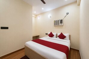 Ein Hotelzimmer mit einem Bett, einem Nachttisch, einer Klimaanlage und einer Wandleuchte.