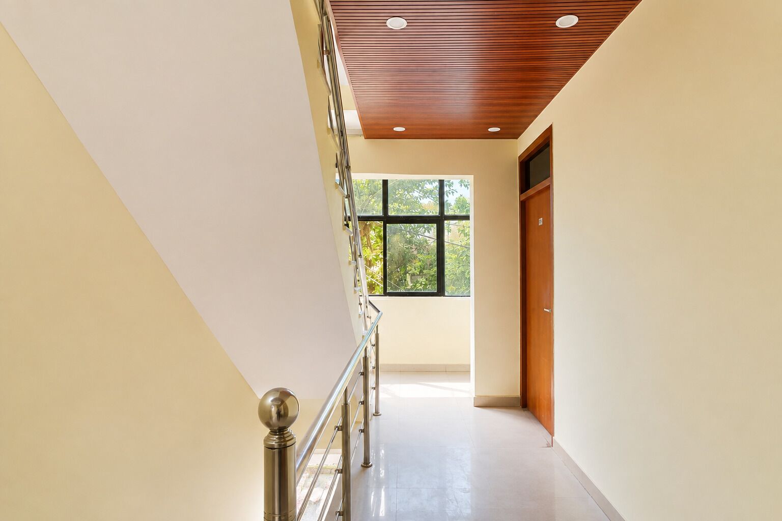 Un interior moderno con una escalera, techo de madera y un amplio ventanal que proporciona luz natural.