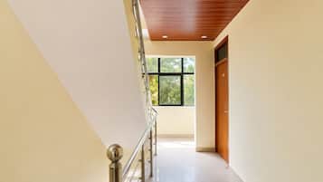 Un interior moderno con una escalera, techo de madera y un amplio ventanal que proporciona luz natural.