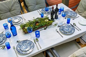 A dining table set with blue and white plates, silverware, and blue glassware, surrounded by greenery and candles. - Breathtaking Franklin Cabin Retreat Near Leiper’s (Franklin)