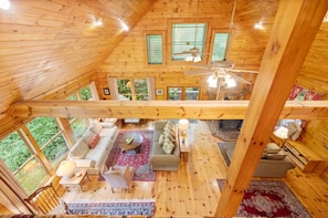 A wooden cabin interior with a high ceiling, a fireplace, and a dining area with a table and chairs. - Breathtaking Franklin Cabin Retreat Near Leiper’s (Franklin)