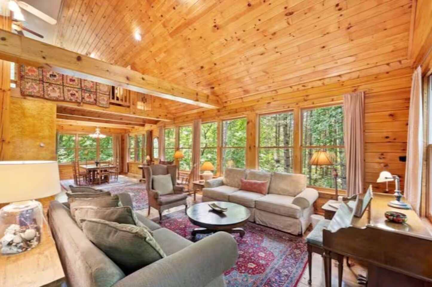 A log cabin interior with a living room, dining area, and large windows.