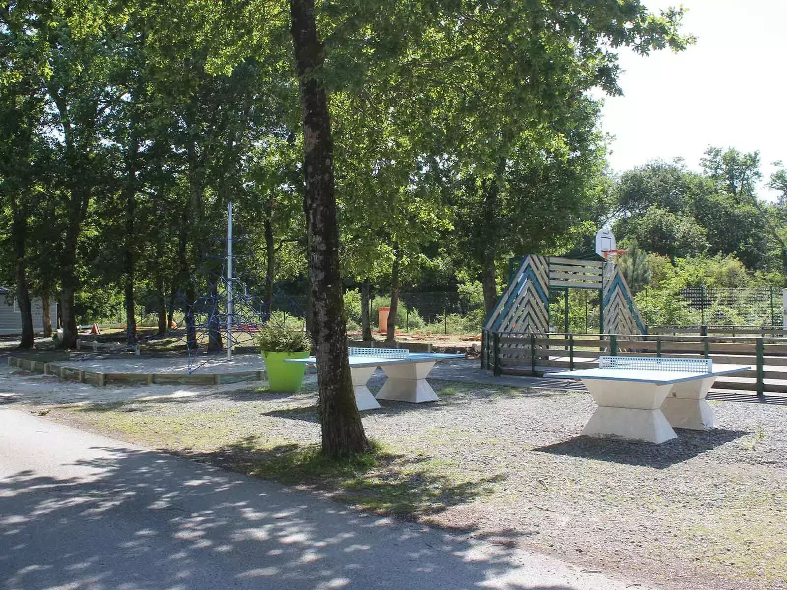 Un parc avec un terrain de basketball, des bancs et des arbres.