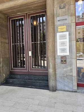 Entrada de edifício com um conjunto de portas duplas, uma placa com 'myevents EVENTS & DIGITAL AGENCY' e placas para 'MORGIONI & SOCCOL AVVOCATI' e 'FORESTERIA'.