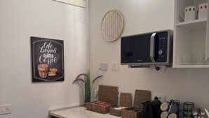 A modern kitchen with a built-in microwave, a clock, and a coffee-themed artwork.