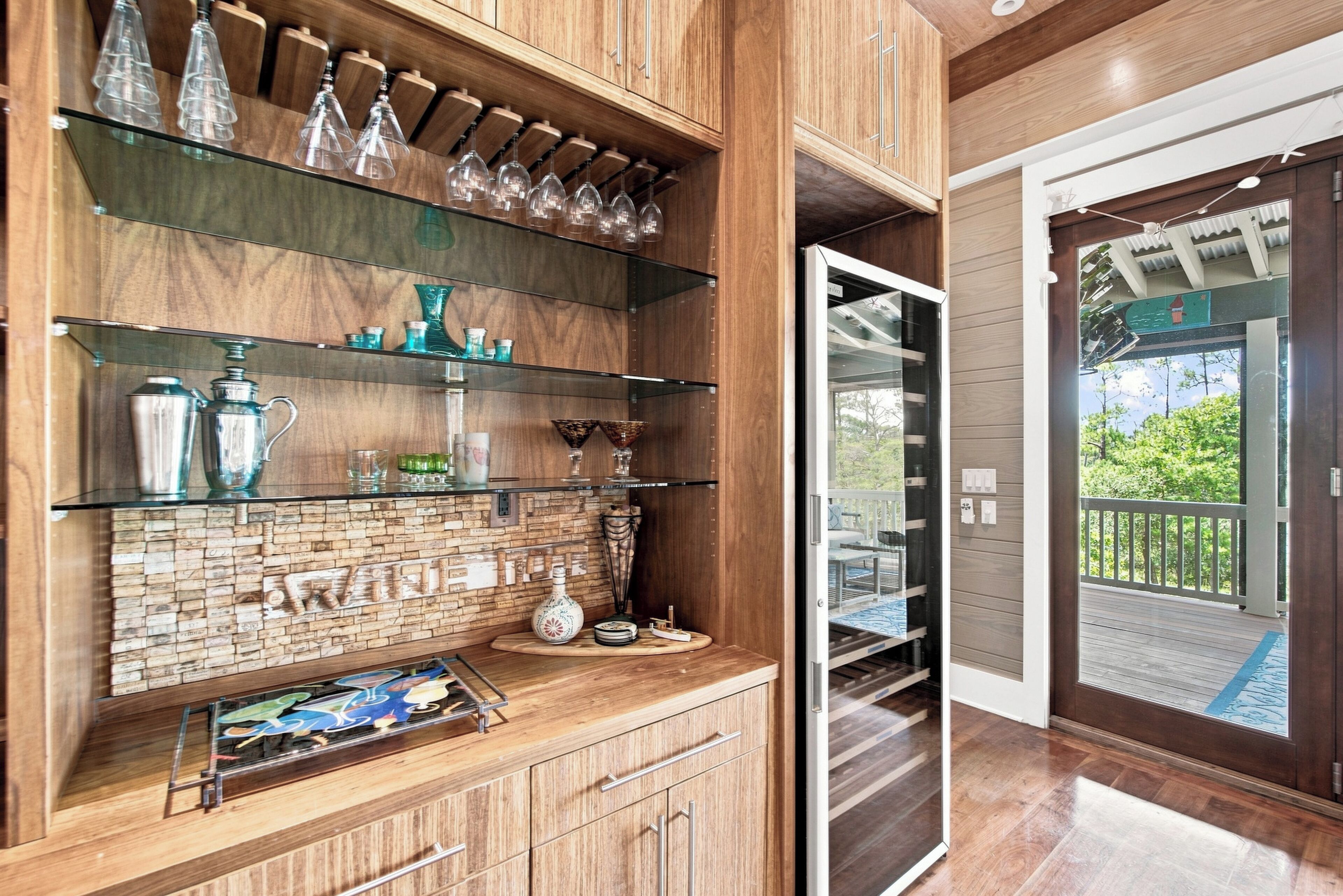 A bar area with wooden shelves, glassware, and a cork wall.