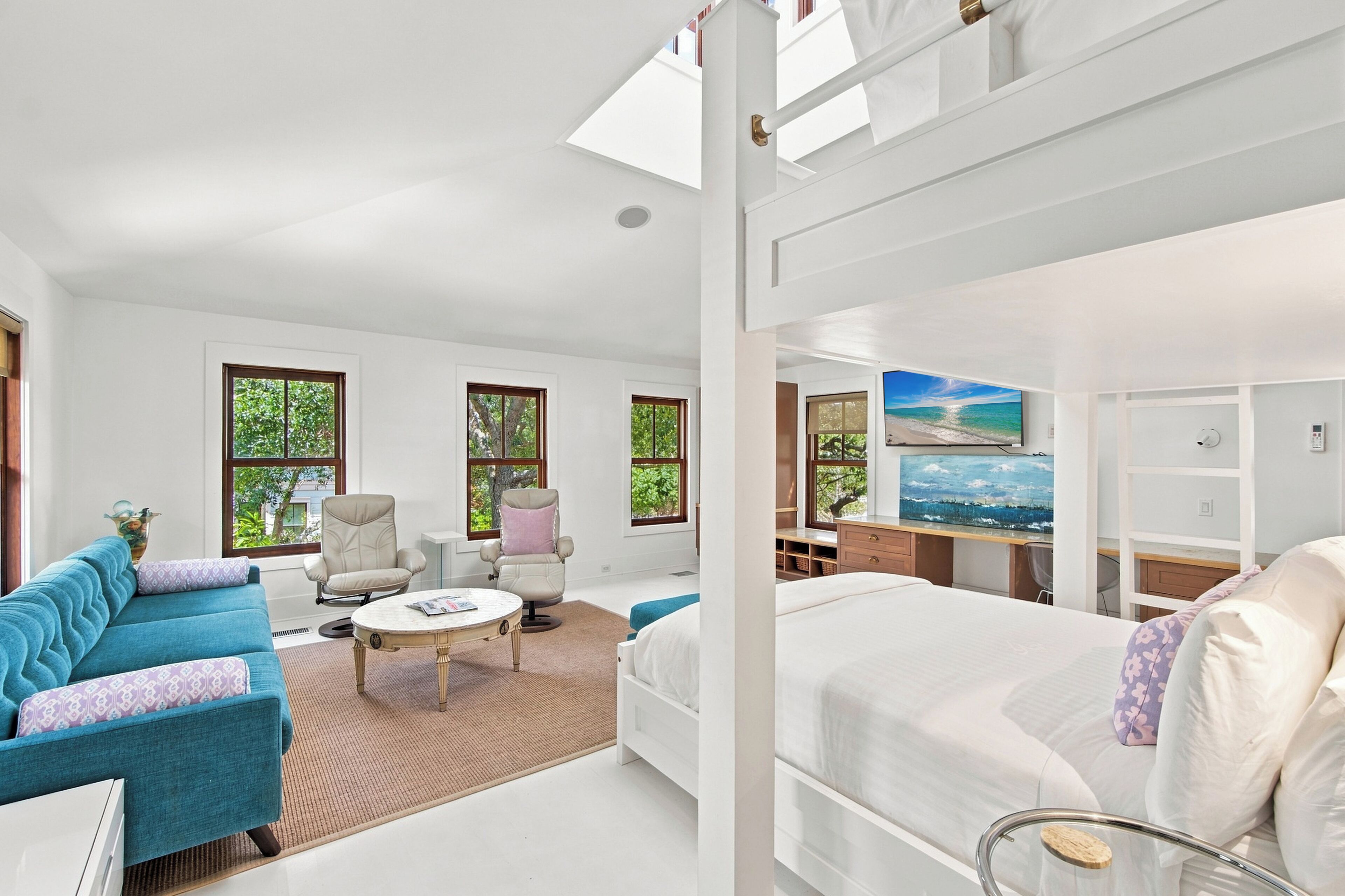 Une chambre d’hôtel moderne, dotée d’un grand lit, d’un canapé, d’un bureau et offrant une vue sur l’extérieur grâce à ses fenêtres.