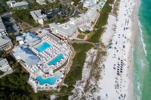 Oversigtsbillede af et resort med flere swimmingpools, en strand og en boardwalk, der fører til kysten.