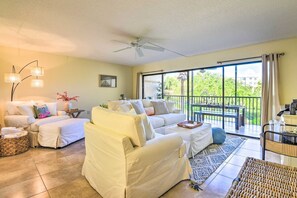 A spacious living area with a sofa, a chair, a coffee table, and a balcony with a table and chairs. - Midnight Cove II 423F (Siesta Key)