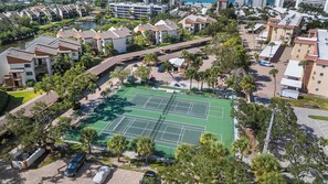 An aerial view of a residential area with a tennis court surrounded by apartment buildings and palm trees. - Midnight Cove II 423F (Siesta Key)