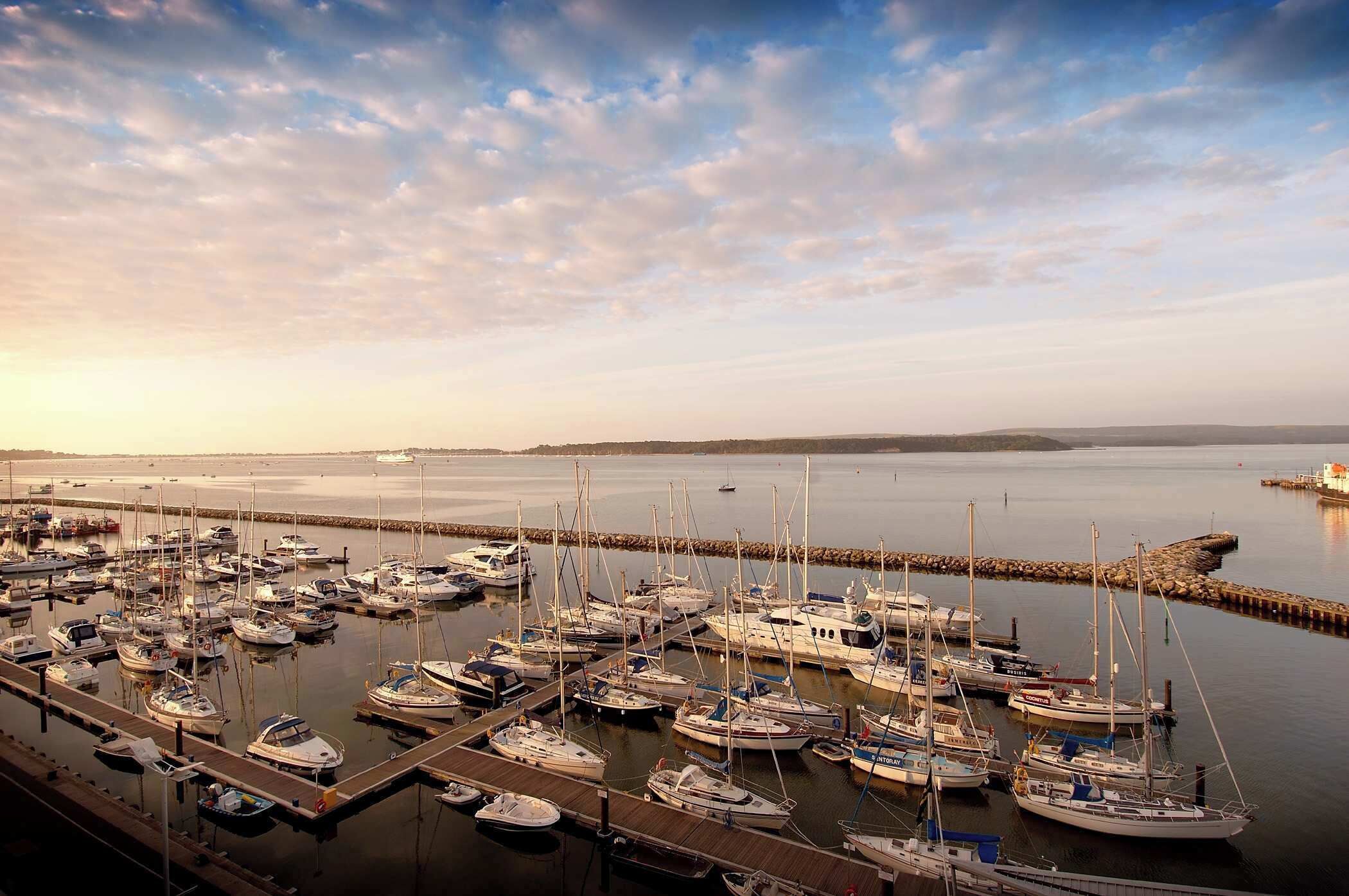 A marina with numerous boats docked at wooden piers.