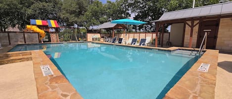 Piscina con sillas de descanso y zona de juegos para niños.