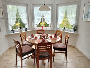 A dining area with a round table, six chairs, and a hanging light fixture.