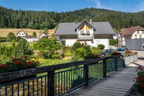 A hotel with a balcony, surrounded by greenery and a wooden deck.