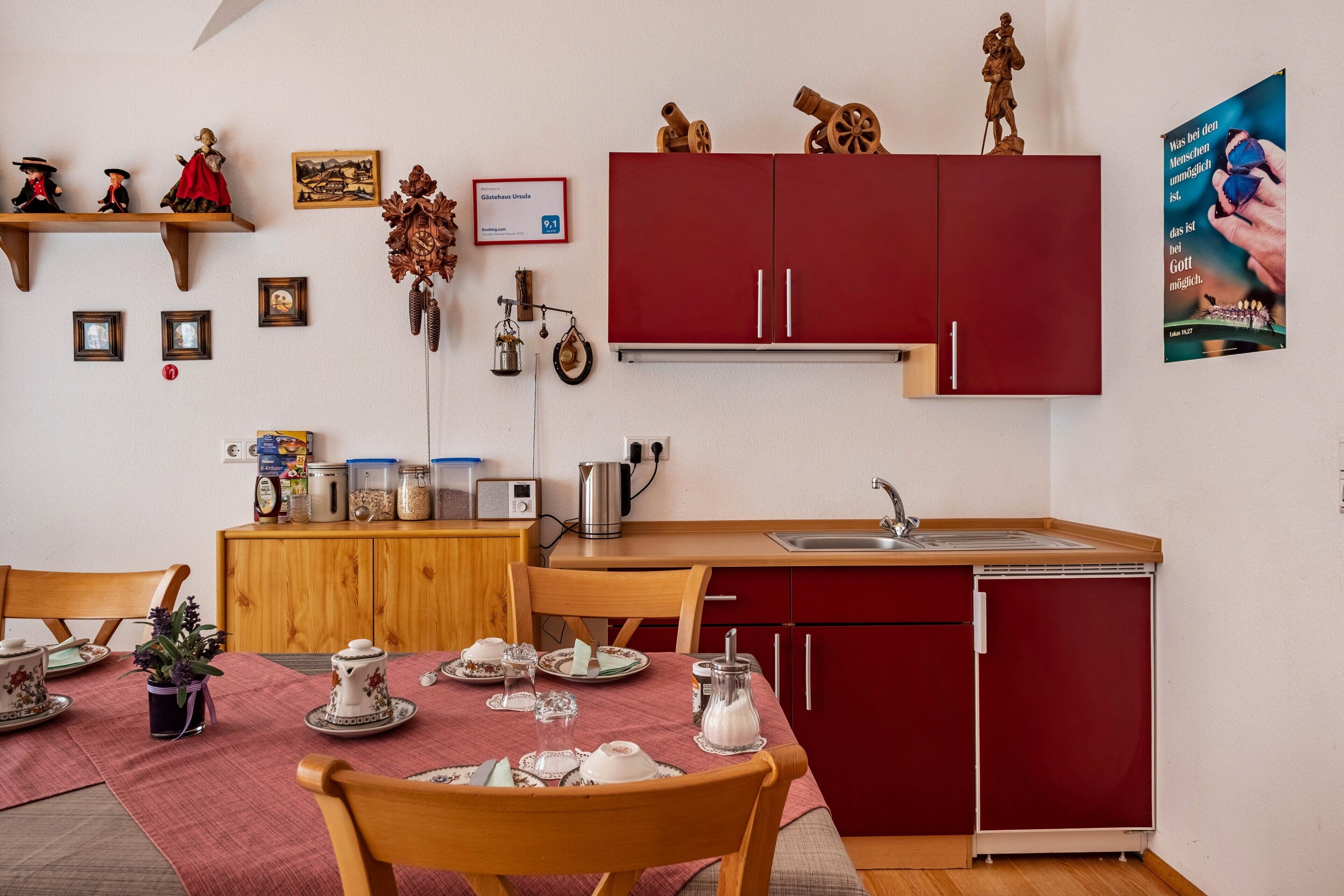 A compact kitchen with wooden cabinets, a dining table set with dishes, and a red refrigerator.