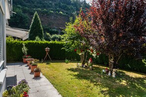 Ein Garten mit Kübelpflanzen, einer Bank und einer Statue einer Figur.